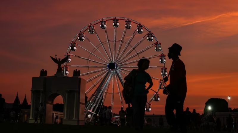 entidad ligada — Una noria gigante se recorta contra un cielo anaranjado durante el atardecer en una feria de la celebración del 250 aniversario de Estados Unidos. Foto de: CNN en Español