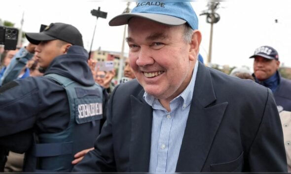 El alcalde de Lima, Rafael López Aliaga, sonríe durante un evento público mientras es escoltado por personal de seguridad. Foto de: La República