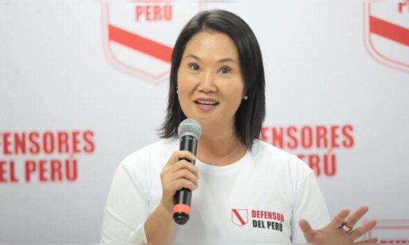 credencial Keiko Fujimori — Una mujer con camiseta blanca y logo de 'Defensor del Perú' sostiene un micrófono frente a un fondo institucional. Foto de: La República