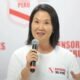 credencial Keiko Fujimori — Una mujer con camiseta blanca y logo de 'Defensor del Perú' sostiene un micrófono frente a un fondo institucional. Foto de: La República