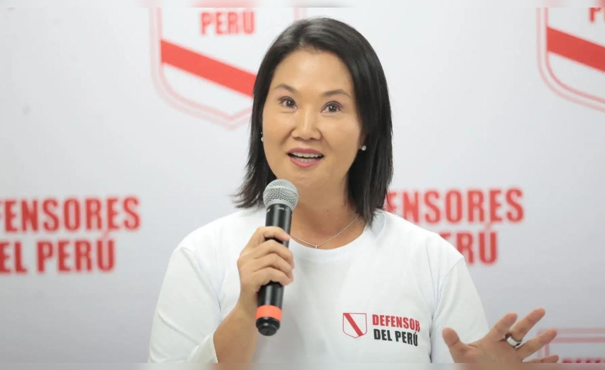 credencial Keiko Fujimori — Una mujer con camiseta blanca y logo de 'Defensor del Perú' sostiene un micrófono frente a un fondo institucional. Foto de: La República