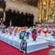 Ministerio Público — Una iglesia decorada con flores coloridas y retratos de personas sobre bloques blancos frente a un altar dorado. Foto de: El Búho