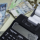 Peruanos usarán — Una calculadora con un rollo de papel muestra el número 4200 junto a billetes de cien pesos argentinos y monedas doradas. Foto de: Perú21