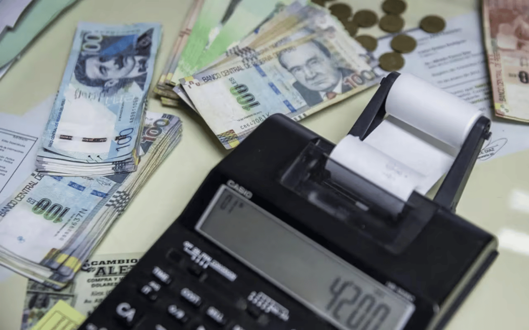 Peruanos usarán — Una calculadora con un rollo de papel muestra el número 4200 junto a billetes de cien pesos argentinos y monedas doradas. Foto de: Perú21