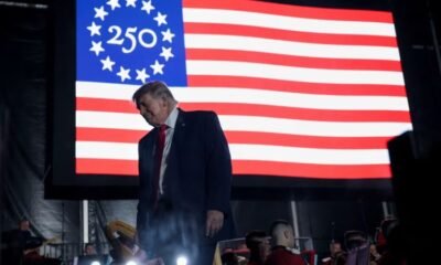 Donald Trump aparece frente a una bandera conmemorativa del 250 aniversario de Estados Unidos en medio de las quejas por la organización del evento. Foto de: CNN en Español