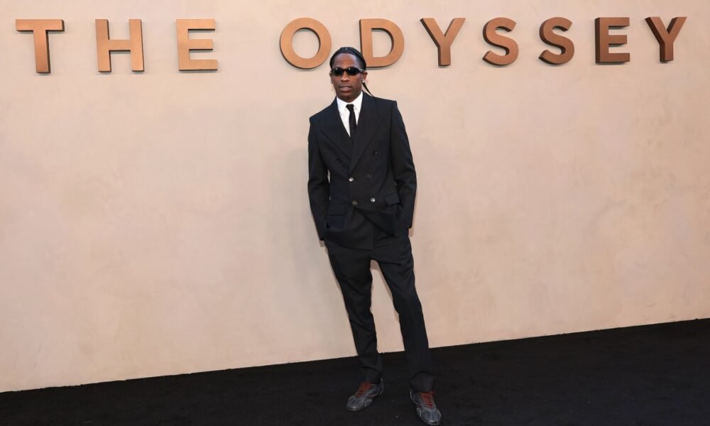 El artista Travis Scott posa frente a un muro con el título de su proyecto 'The Odyssey'. Foto de: Dimitrios Kambouris/Getty Images for Universal Pictures