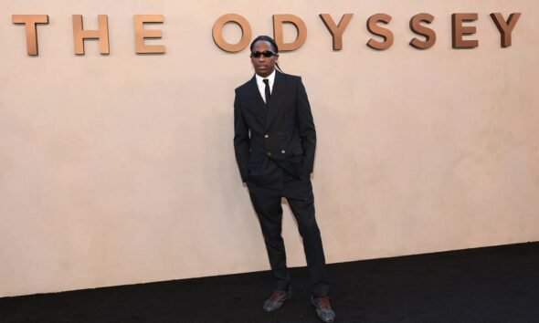 El artista Travis Scott posa frente a un muro con el título de su proyecto 'The Odyssey'. Foto de: Dimitrios Kambouris/Getty Images for Universal Pictures