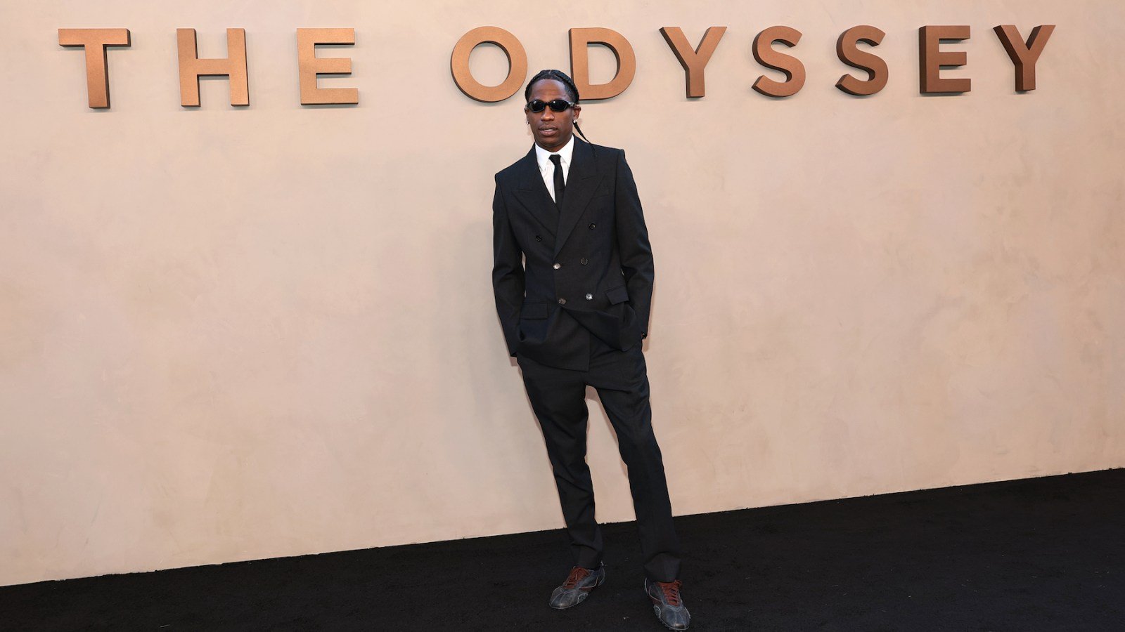 El artista Travis Scott posa frente a un muro con el título de su proyecto 'The Odyssey'. Foto de: Dimitrios Kambouris/Getty Images for Universal Pictures
