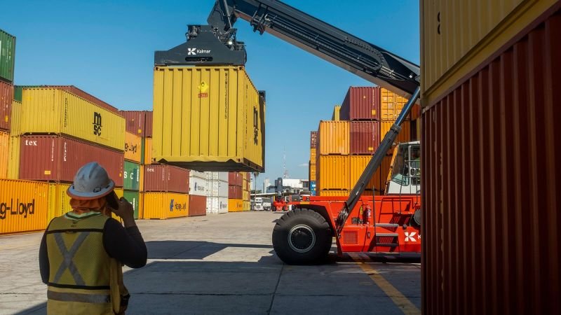 obstáculos legales — Una grúa mueve contenedores en un puerto, simbolizando el flujo comercial afectado por las posibles tensiones en el acuerdo T-MEC. Foto de: CNN en Español