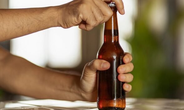 Una persona abre una botella de cerveza, ilustrando la venta de bebidas alcohólicas sin restricciones de horario. Foto de: Gestión