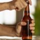 Una persona abre una botella de cerveza, ilustrando la venta de bebidas alcohólicas sin restricciones de horario. Foto de: Gestión
