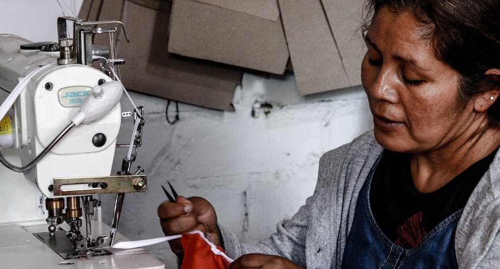 Lima Metropolitana — Una mujer de rasgos asiáticos opera una máquina de coser industrial mientras sostiene una pieza de tela roja. Foto de: Gestión