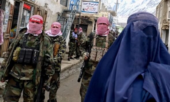 crisis Afganistán — Soldados con pasamontañas y una mujer con hiyab en una calle de Afganistán reflejan la situación actual tras la llegada de los talibanes. Foto de: CNN en Español