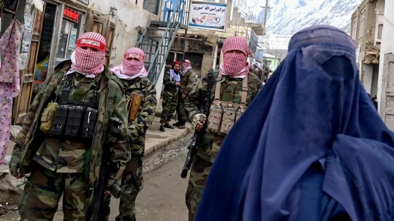 crisis Afganistán — Soldados con pasamontañas y una mujer con hiyab en una calle de Afganistán reflejan la situación actual tras la llegada de los talibanes. Foto de: CNN en Español