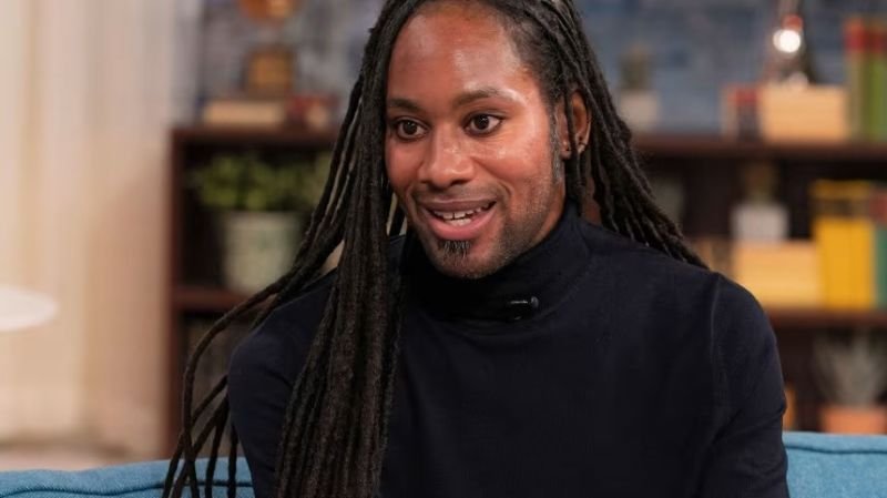 abuso sostenido Jason Arday — Retrato de un hombre con rastas largas y una sonrisa, vistiendo un suéter de cuello alto oscuro. Foto de: CNN en Español