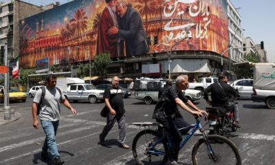 Irán rechaza — Una gran valla publicitaria con imágenes de líderes iraníes preside una calle concurrida en Irán, reflejando la resistencia del país ante las presiones externas. Foto de: Infobae