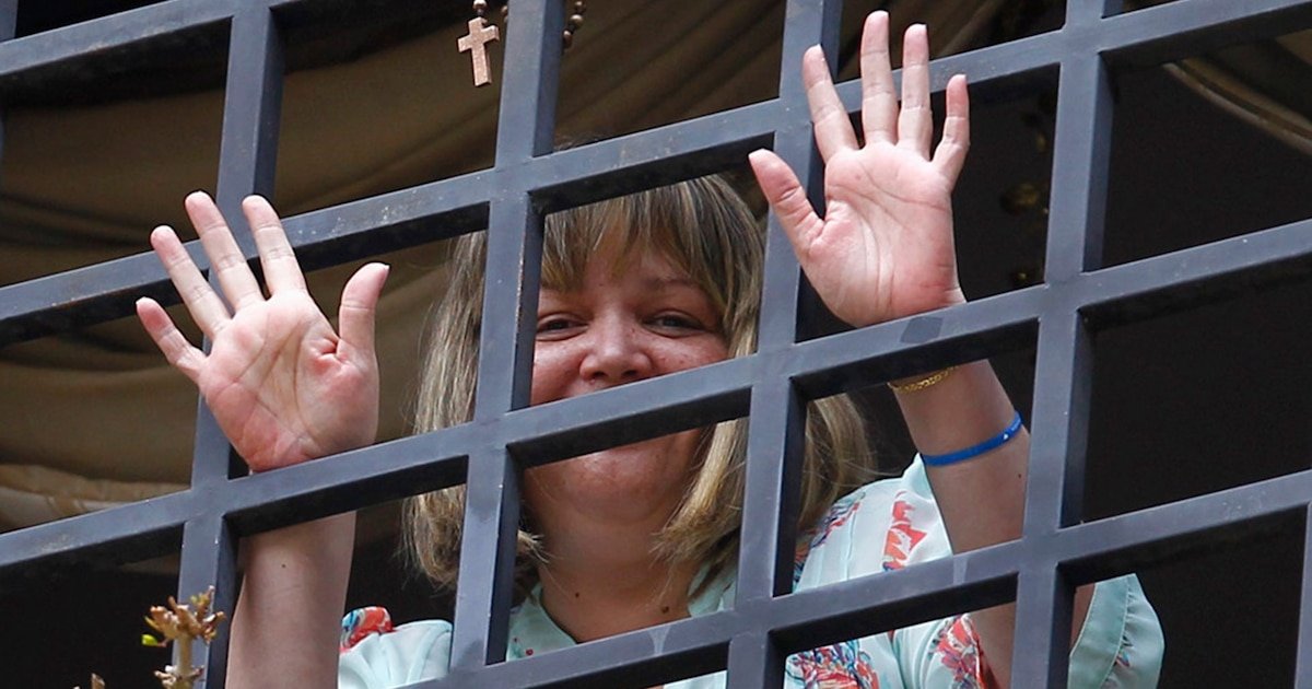 Una mujer sonríe tras una reja metálica en un contexto que evoca la liberación de la jueza María Lourdes Afiuni. Foto de: Infobae