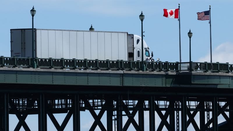 productos canadienses — Un camión de carga circula por un puente con banderas de Canadá y Estados Unidos, simbolizando el comercio entre ambas naciones. Foto de: CNN en Español