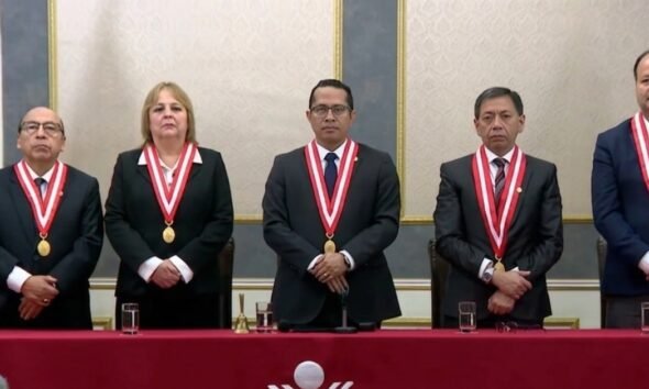valla electoral — Cinco personas con trajes oscuros y medallas ceremoniales posan en una mesa larga frente a una bandera de México. Foto de: Exitosa Noticias