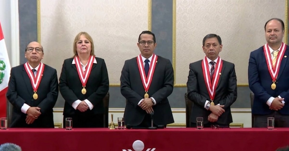 valla electoral — Cinco personas con trajes oscuros y medallas ceremoniales posan en una mesa larga frente a una bandera de México. Foto de: Exitosa Noticias