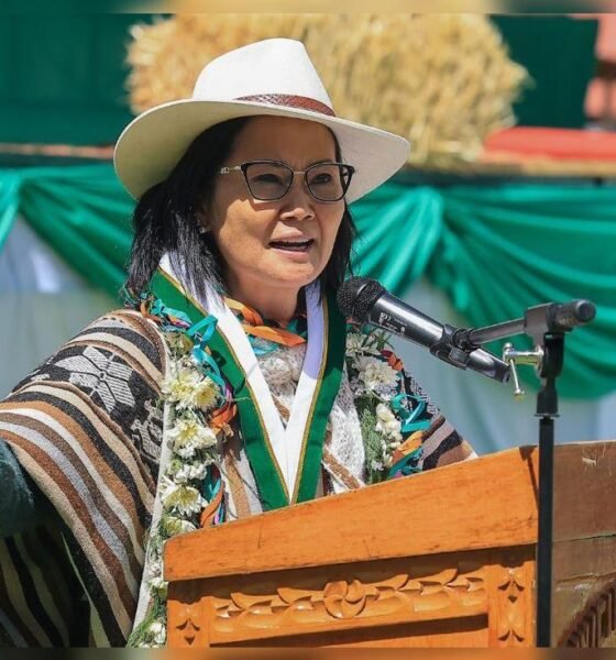 seguridad ciudadana — Una mujer con gafas, sombrero blanco y un sarape colorido habla frente a un micrófono en un podio de madera. Foto de: La República