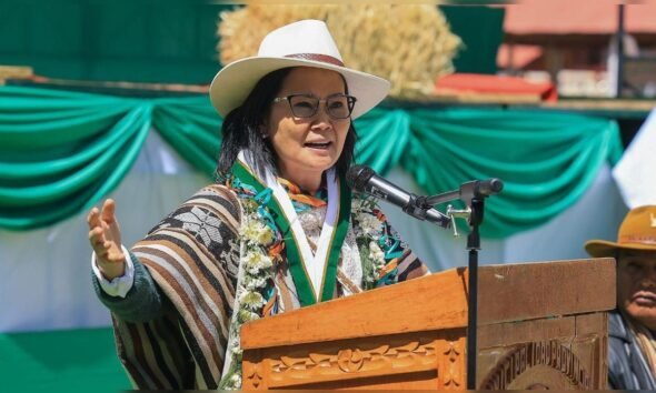 seguridad ciudadana — Una mujer con gafas, sombrero blanco y un sarape colorido habla frente a un micrófono en un podio de madera. Foto de: La República