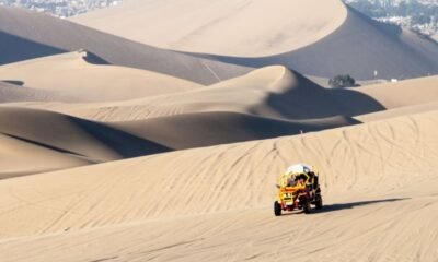 Edunastours Nasca — Un vehículo todoterreno de color amarillo y negro circula sobre una extensa duna de arena en un desierto. Foto de: Gestión