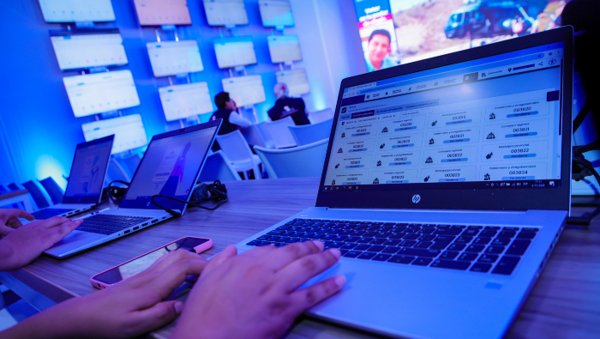 actas electorales — Una persona utiliza una computadora portátil con una interfaz de gestión de datos en una oficina con múltiples monitores. Foto de: El Peruano