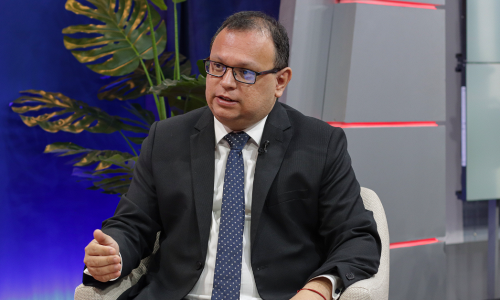 incendios forestales — Un hombre con gafas y traje oscuro habla en un estudio de televisión con una planta decorativa al fondo. Foto de: Exitosa Noticias